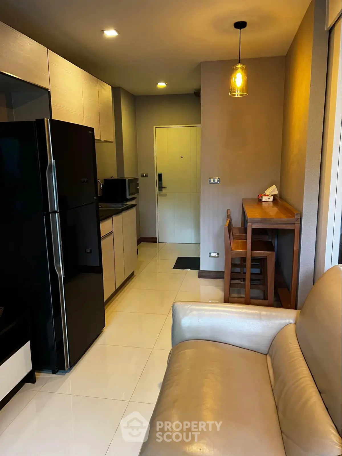 Modern apartment interior with sleek kitchen and cozy living area, featuring stylish lighting and contemporary furniture.