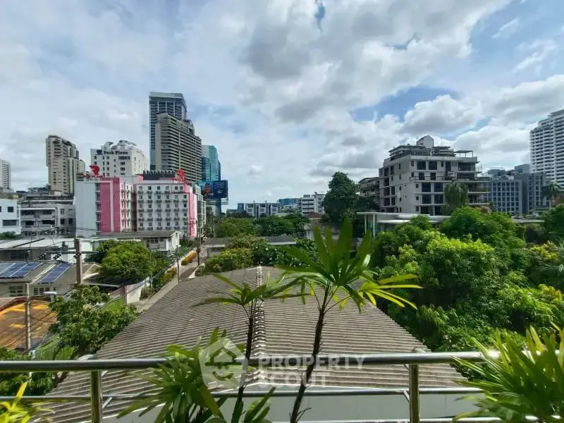 Stunning cityscape view from a balcony overlooking lush greenery and modern buildings.