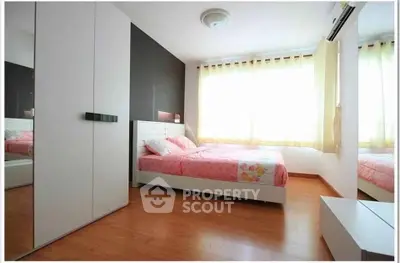 Bright and cozy bedroom with wooden flooring and large windows.