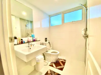 Modern bathroom with sleek fixtures and large mirror in a bright, airy space.