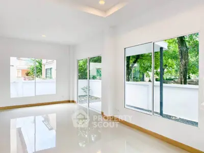 Spacious and bright living room with large windows and garden view.