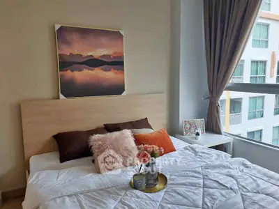 Cozy bedroom with modern decor and large window offering natural light and city view.
