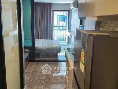 Modern studio apartment with compact kitchen and cozy bedroom, featuring a balcony view.