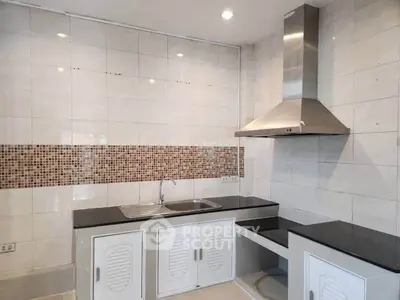 Modern kitchen with sleek countertops and stainless steel range hood in a stylish open layout.