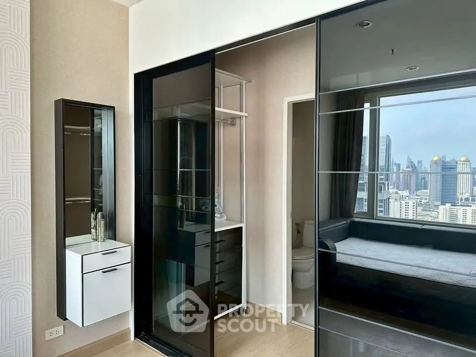 Modern bedroom with city view, featuring sleek glass wardrobe and stylish decor.