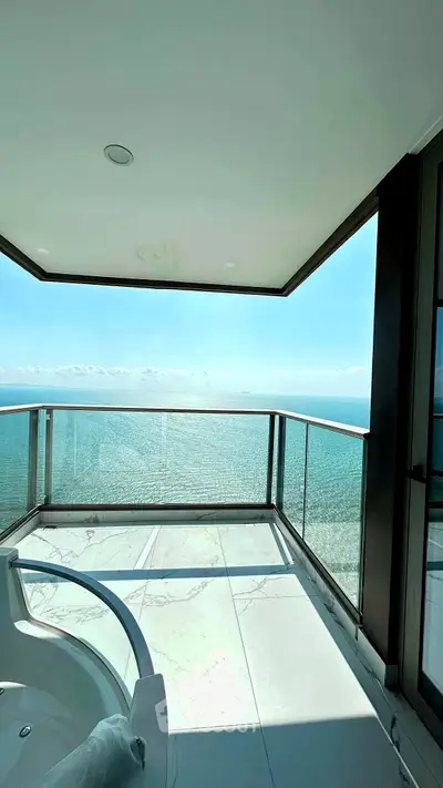 Luxurious oceanfront balcony with stunning sea view and modern glass railing.