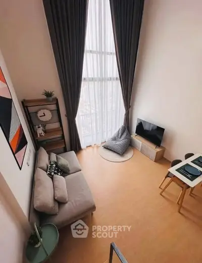 Modern living room with high ceiling, large window, cozy sofa, and stylish decor in a contemporary apartment.