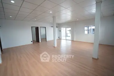 Spacious open-plan room with wooden flooring and ample natural light