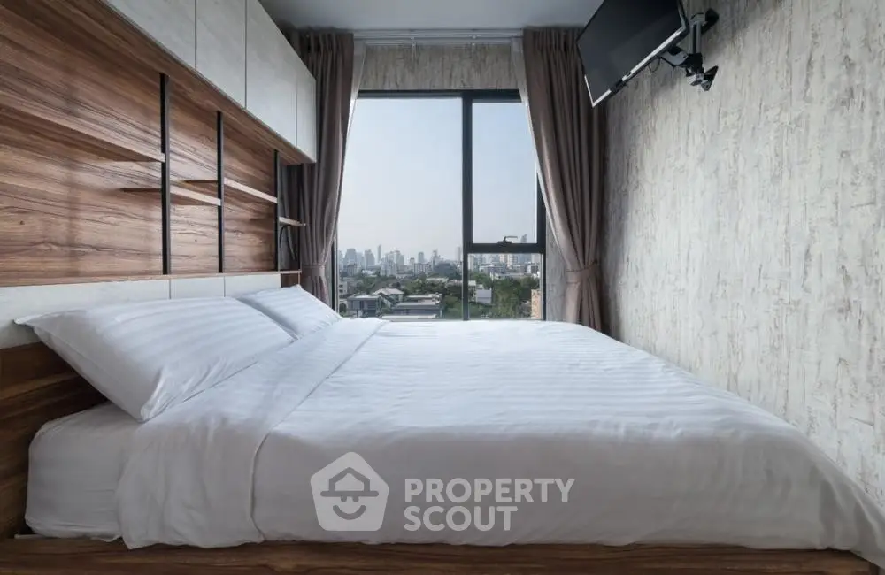 Modern bedroom with city view, featuring stylish decor and large window for natural light.