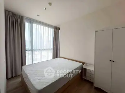 Spacious bedroom with large window and modern furniture