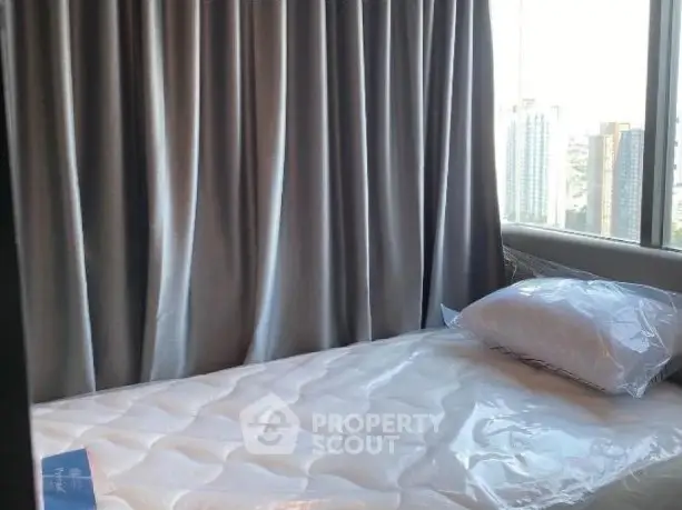 Cozy bedroom with city view and large windows, featuring a comfortable bed and elegant curtains.