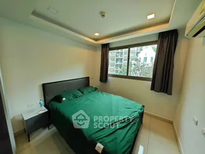 Modern bedroom with green bedding and large window in urban apartment