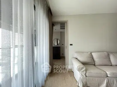 Bright living room with cozy sofa and sheer curtains, offering a glimpse into a modern interior design.