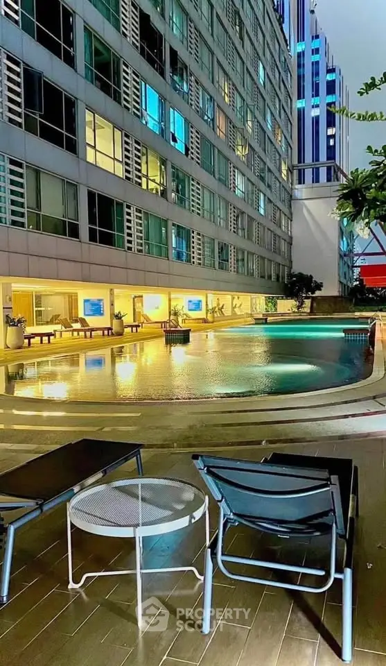 Luxurious apartment building with illuminated poolside area and modern architecture.
