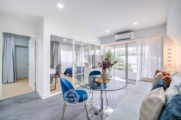 Modern living room with glass partition, stylish decor, and natural light in a contemporary apartment.