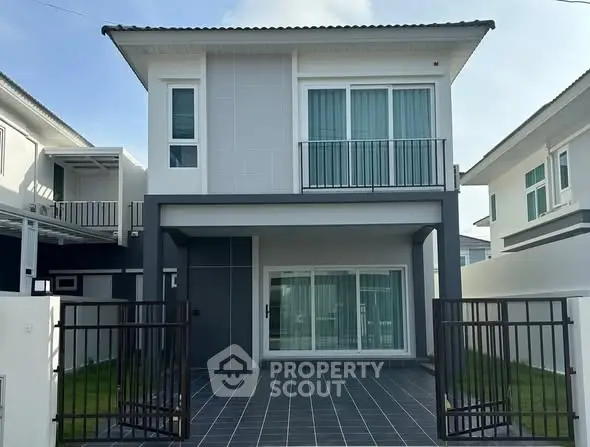 Modern two-story house with sleek design and gated driveway in a suburban neighborhood.