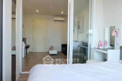 Modern bedroom with sliding glass doors and cozy living area in a stylish apartment.