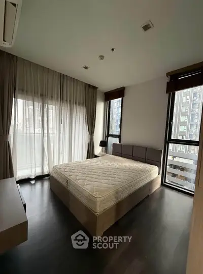 Spacious bedroom with large windows and modern decor in a high-rise apartment.