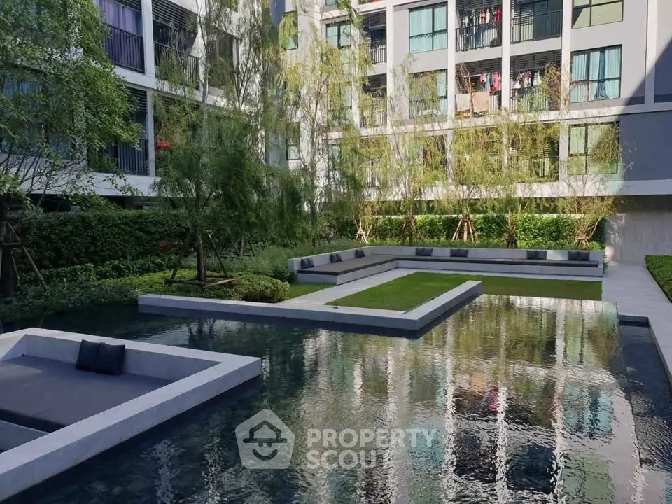 Modern apartment complex with serene water feature and lush greenery
