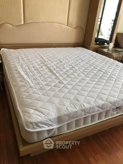 Spacious bedroom with elegant wooden flooring and a luxurious king-size bed.