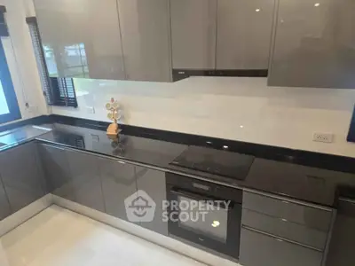 Modern kitchen with sleek cabinetry and built-in oven, featuring a minimalist design.