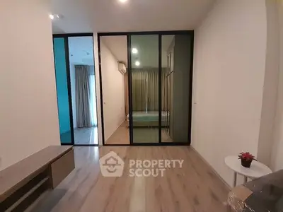 Spacious and modern living room with sleek wooden flooring, large glass sliding doors leading to a cozy balcony, and ample natural light.
