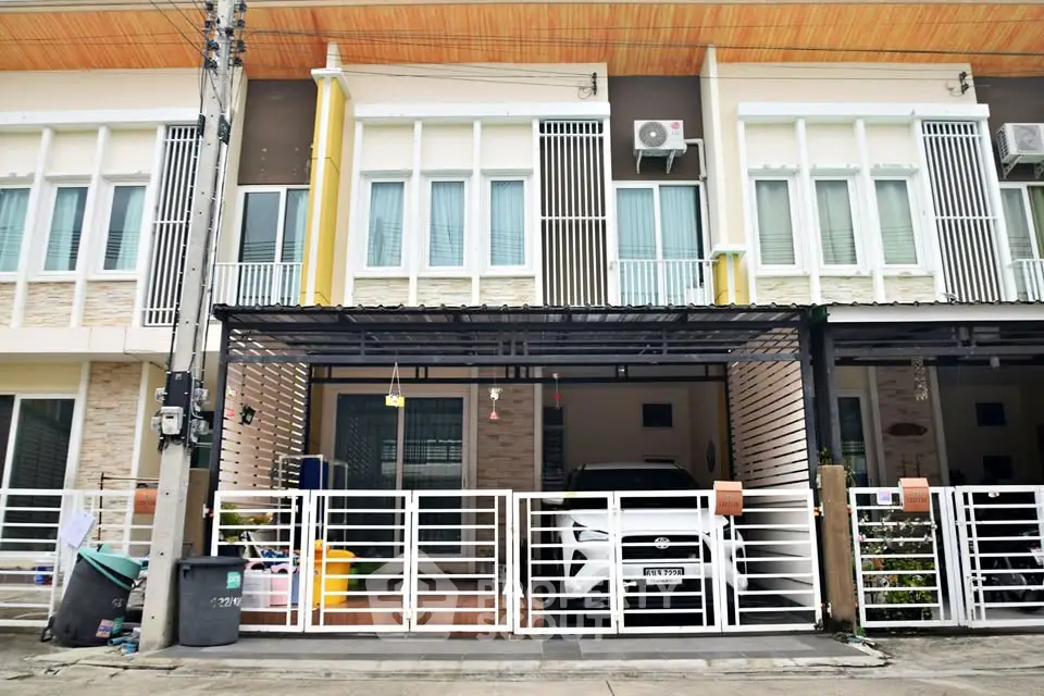 Modern townhouse exterior with carport and gated entrance in urban setting.