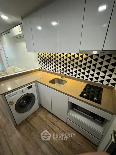 Modern kitchen with sleek cabinets, washing machine, and stylish backsplash.