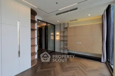 Modern interior with elegant wooden flooring and built-in shelving, featuring large windows for natural light.