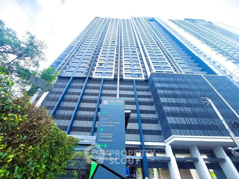 Modern high-rise building with sleek design and ample parking facilities.