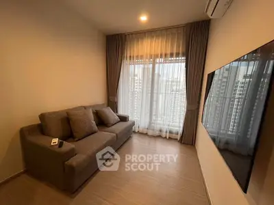 Cozy living room with modern sofa and large TV, city view through window.