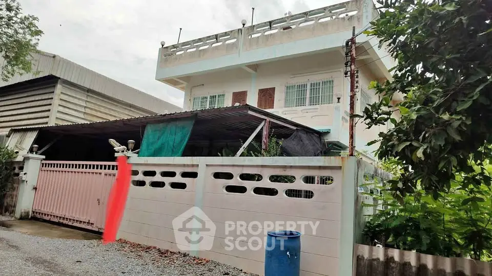 Charming two-story house with gated entrance and lush greenery, perfect for family living.