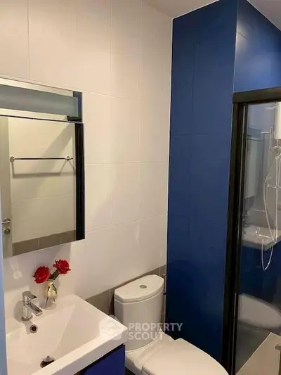 Modern bathroom with blue accents, sleek fixtures, and a glass shower enclosure.