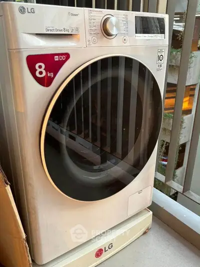 Modern LG washing machine on apartment balcony, showcasing convenient laundry setup.