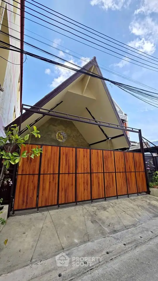 Modern house exterior with unique triangular roof and wooden gate, showcasing contemporary architecture.