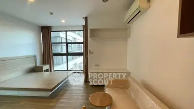 Modern living room with large windows and minimalist furniture in a high-rise apartment.