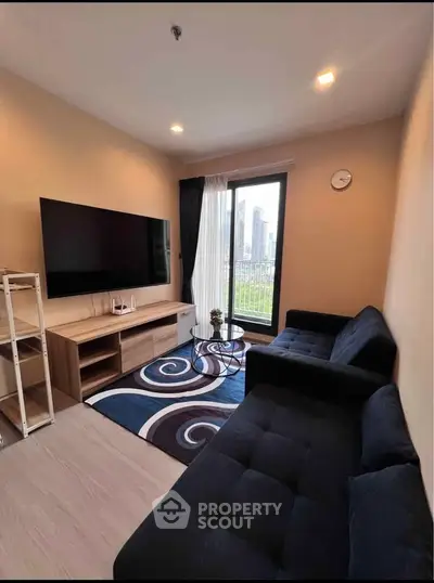 Modern living room with large TV, stylish sofas, and city view through window.