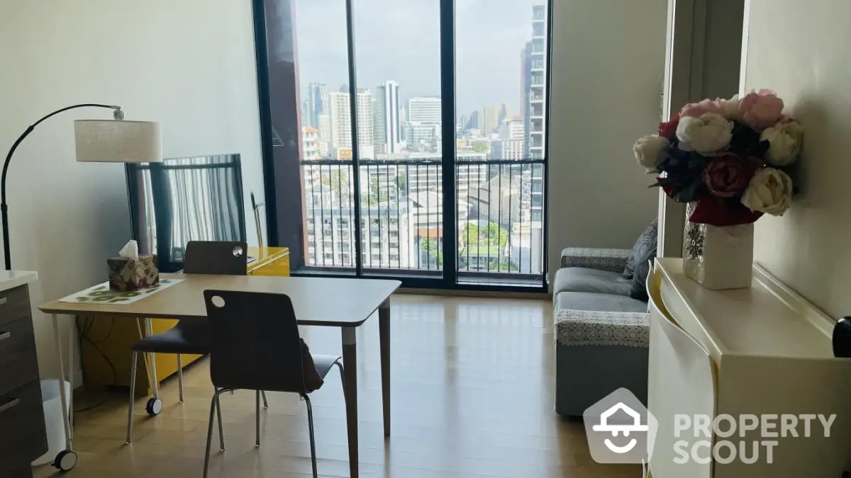 Modern living room with city view, featuring stylish furniture and large windows.