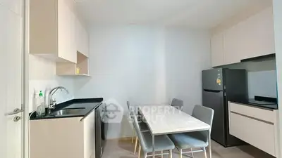 Modern kitchen with dining area, featuring sleek cabinetry and appliances.