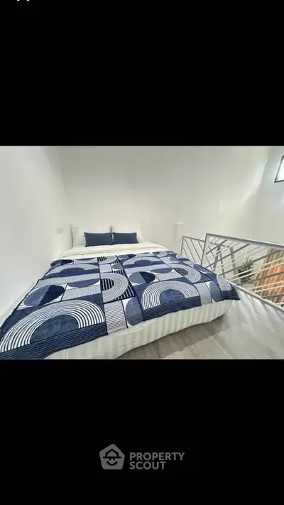 Modern bedroom with stylish bedding and sleek railing in a bright, minimalist space.