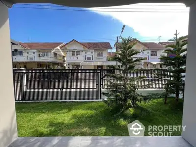 Charming residential view with lush green lawn and modern fence in suburban neighborhood.