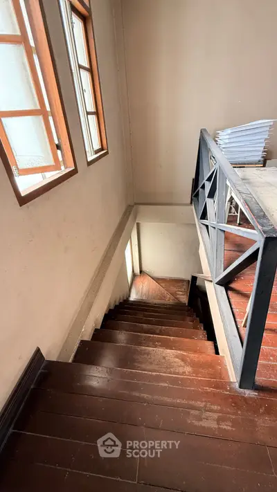 Charming wooden staircase with natural light from windows, perfect for cozy home ambiance.