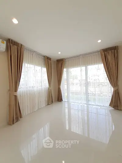 Spacious corner unit living room with large windows and elegant curtains.