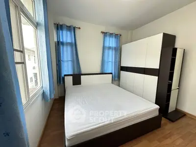 Bright bedroom with large windows and modern furniture in a cozy apartment.