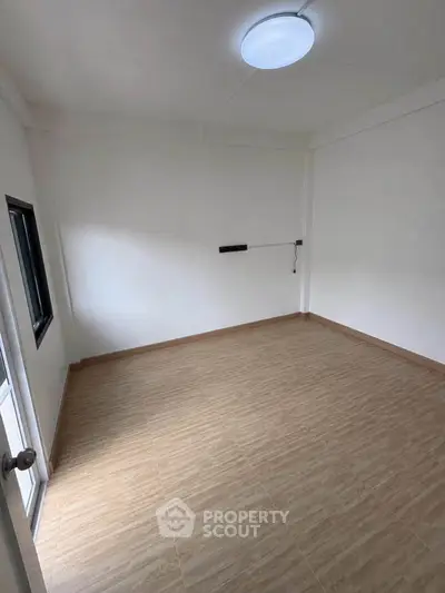 Spacious empty room with wooden flooring and natural light, perfect for customization.