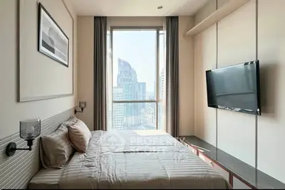 Modern bedroom with city view, featuring a wall-mounted TV and stylish decor.