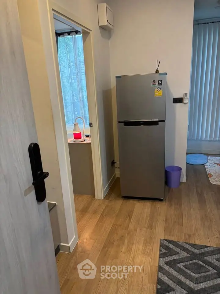 Modern apartment interior with sleek fridge and wooden flooring