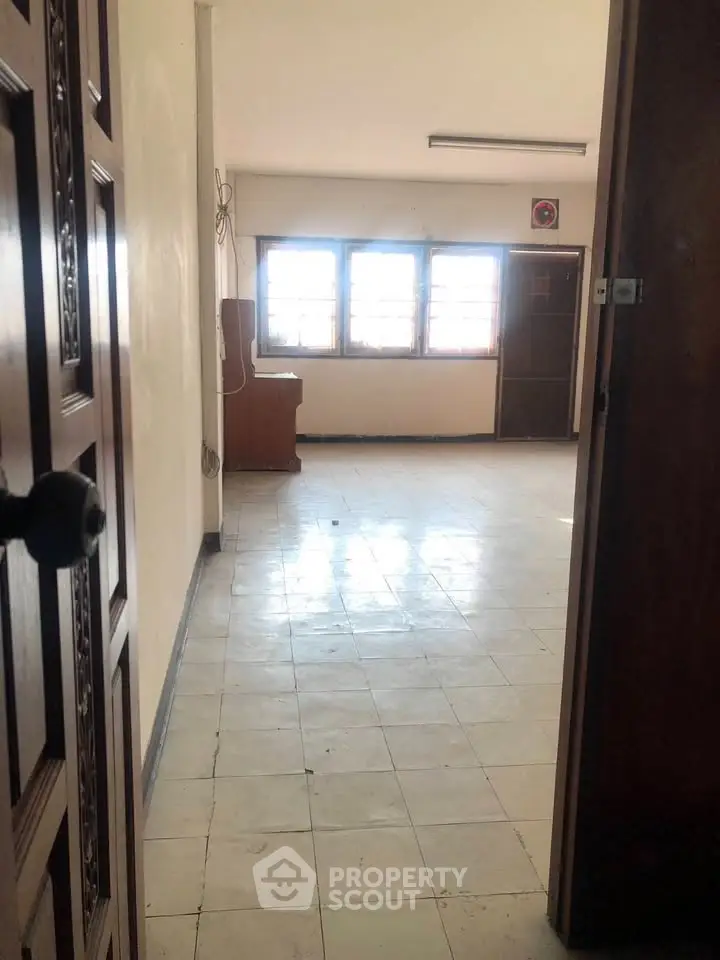 Spacious empty room with tiled flooring and large windows offering natural light.
