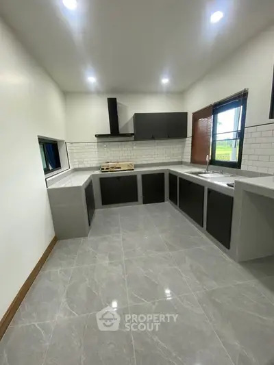 Modern kitchen with sleek cabinetry and tiled backsplash, featuring ample counter space and natural light.