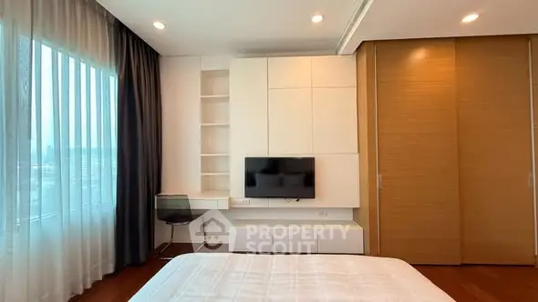 Modern bedroom with sleek design, built-in TV, and large window with city view.